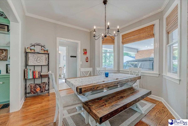 dining space with crown molding, baseboards, light wood-type flooring, and a chandelier