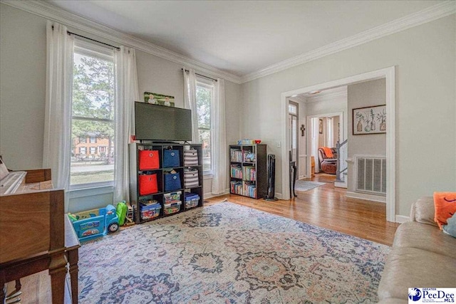 recreation room featuring visible vents, baseboards, crown molding, and wood finished floors