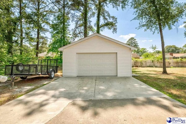 detached garage featuring fence and driveway