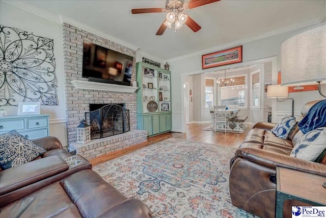 living area featuring a brick fireplace, wood finished floors, crown molding, and ceiling fan