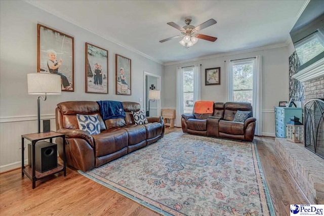 living area featuring light wood-style floors, a ceiling fan, and ornamental molding