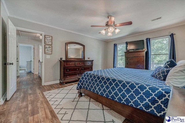 bedroom featuring light wood-type flooring, ornamental molding, visible vents, attic access, and baseboards