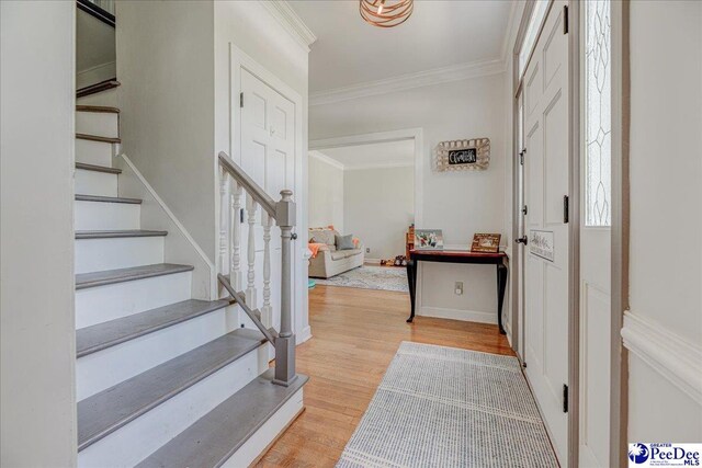 foyer entrance featuring ornamental molding, stairway, and wood finished floors