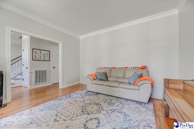 living room featuring wood finished floors, ornamental molding, visible vents, and stairway