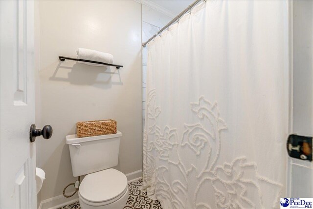 bathroom featuring toilet, curtained shower, and baseboards