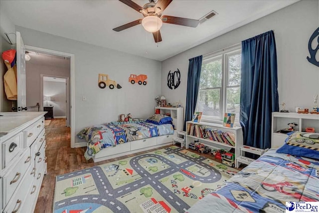 bedroom featuring visible vents, baseboards, a ceiling fan, and wood finished floors