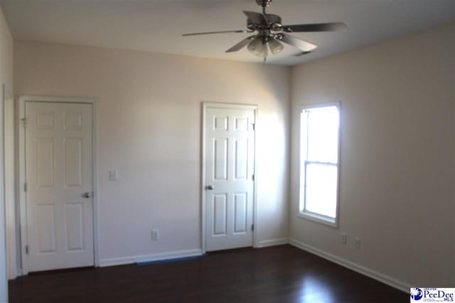 unfurnished bedroom with baseboards, a ceiling fan, and dark wood-style flooring