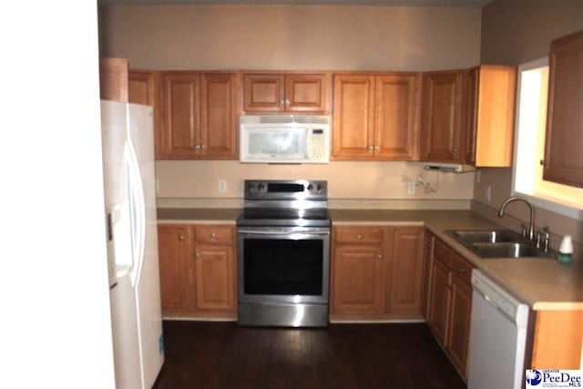 kitchen featuring dark wood finished floors, light countertops, brown cabinetry, white appliances, and a sink