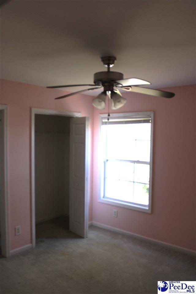 unfurnished bedroom with a closet, baseboards, light colored carpet, and a ceiling fan