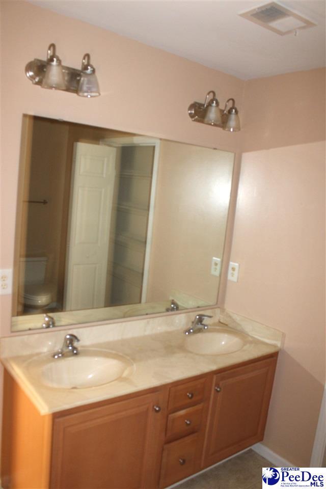 bathroom featuring double vanity, toilet, visible vents, and a sink