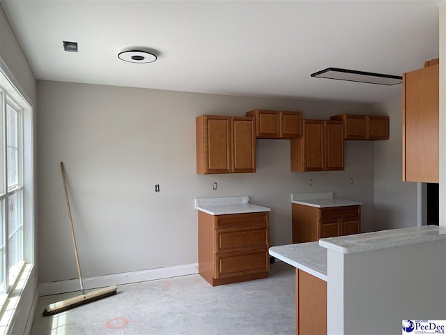 kitchen featuring brown cabinets, baseboards, and plenty of natural light