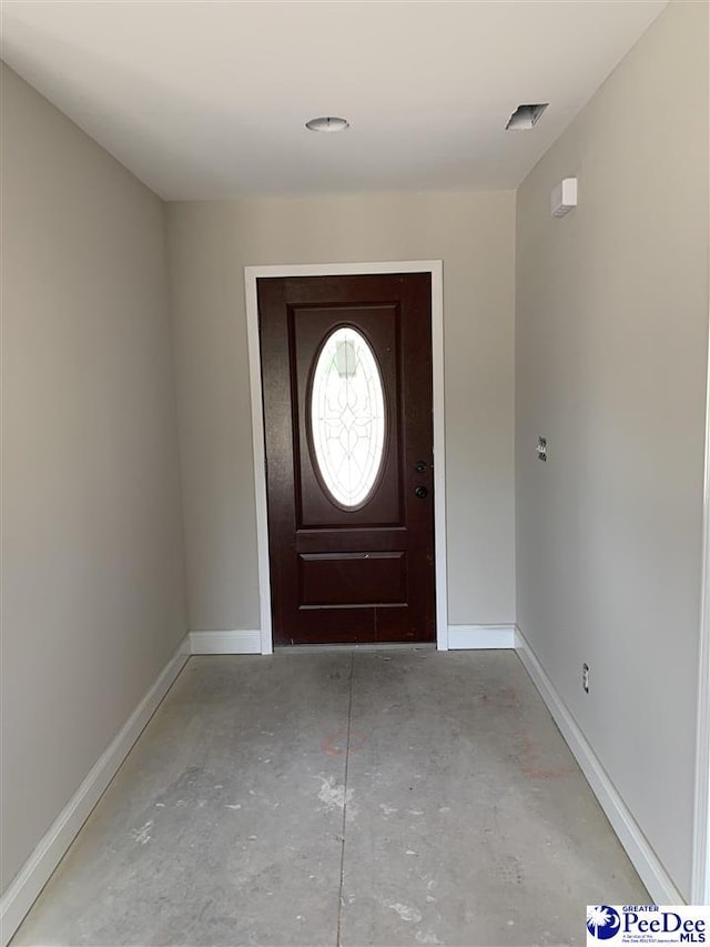 foyer entrance featuring baseboards and concrete floors