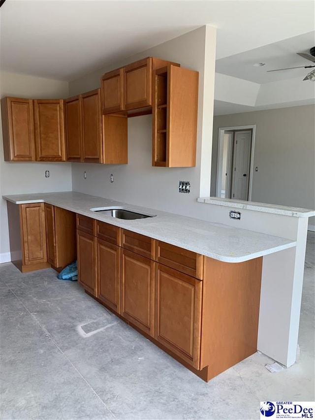 kitchen featuring brown cabinets, a peninsula, and a sink