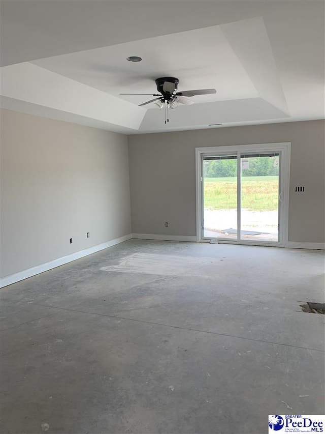 unfurnished room with concrete floors, ceiling fan, a raised ceiling, and baseboards