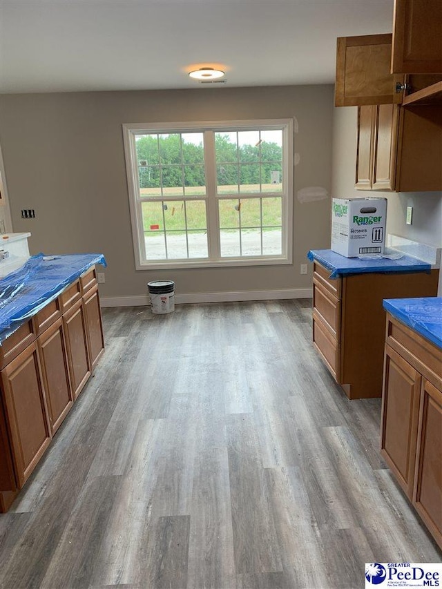 4974 E National Cemetery Rd, Florence, SC 29506 - kitchen with light wood-style floors, brown cabinetry, and baseboards