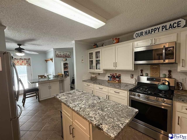 159 Ridge Rd, Cheraw, SC 29512 - kitchen featuring appliances with stainless steel finishes, crown molding, a textured ceiling, decorative backsplash, and glass insert cabinets