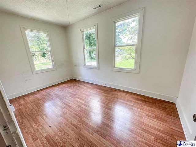 unfurnished room featuring a textured ceiling and light hardwood / wood-style flooring