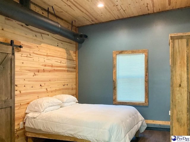 bedroom with wooden ceiling, wood finished floors, recessed lighting, a barn door, and baseboards