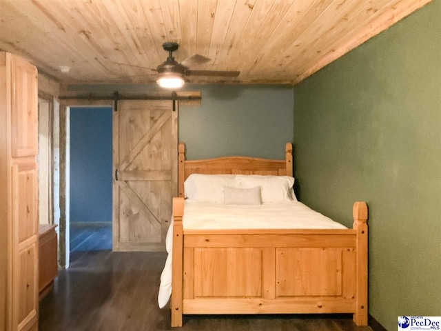 bedroom with a barn door, ceiling fan, dark wood finished floors, and wooden ceiling
