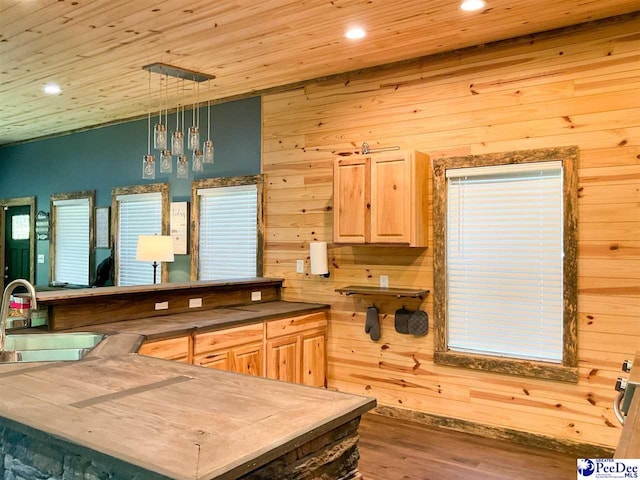 kitchen featuring recessed lighting, a sink, wooden walls, light brown cabinetry, and wood finished floors