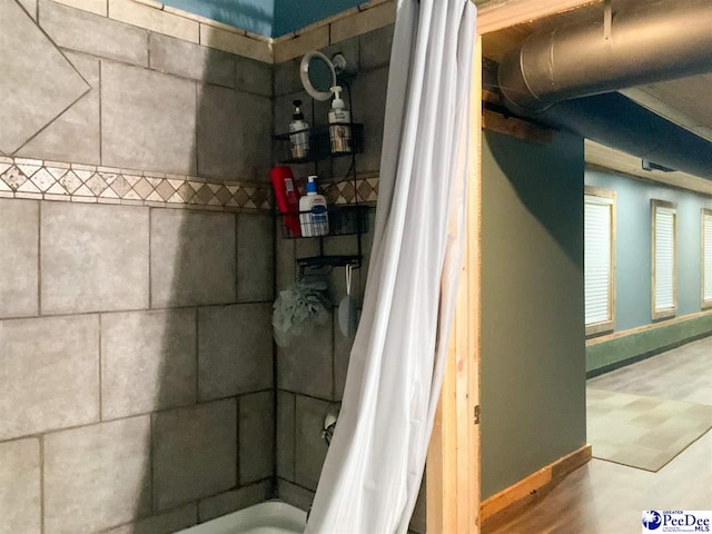 interior space featuring a shower with shower curtain and baseboards