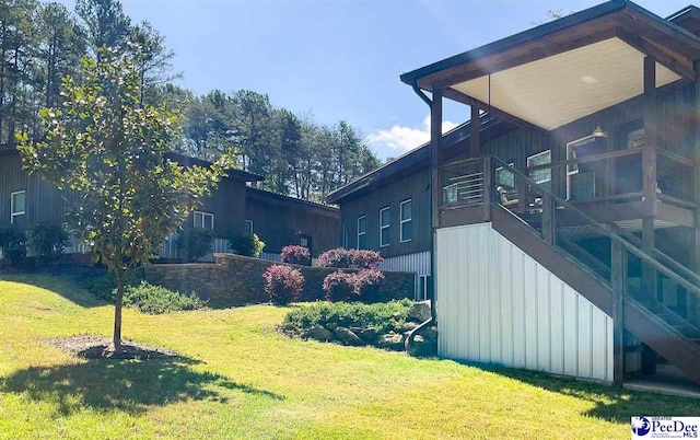 view of property exterior with stairway, a sunroom, and a lawn