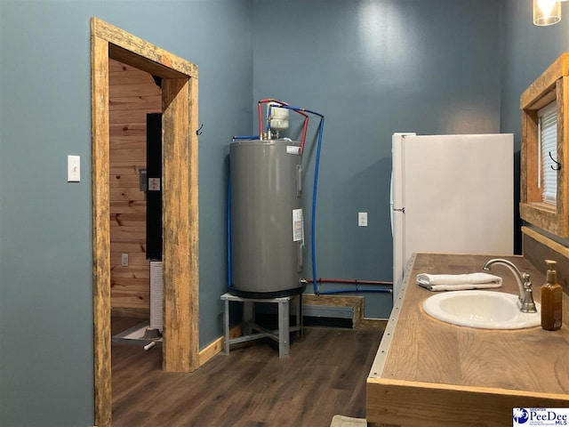 bathroom featuring vanity, baseboards, wood finished floors, and electric water heater
