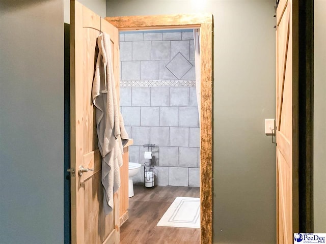 full bath with wood finished floors, toilet, and a shower stall