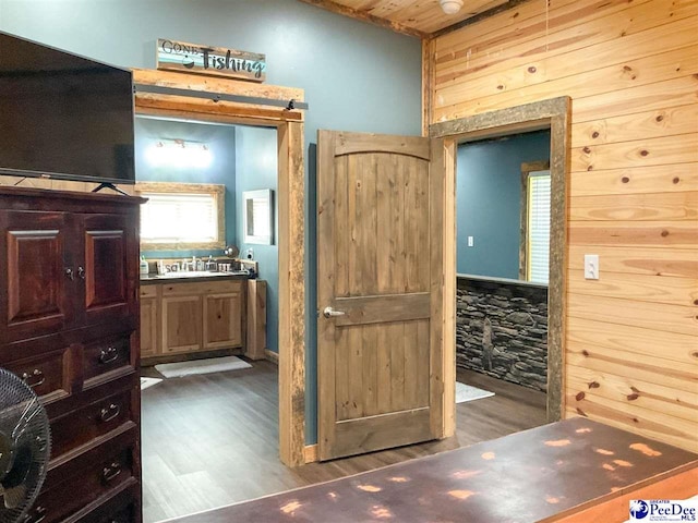 bathroom with wood finished floors, wooden walls, and vanity