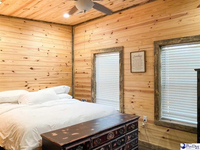bedroom featuring a ceiling fan, wooden walls, and wood ceiling