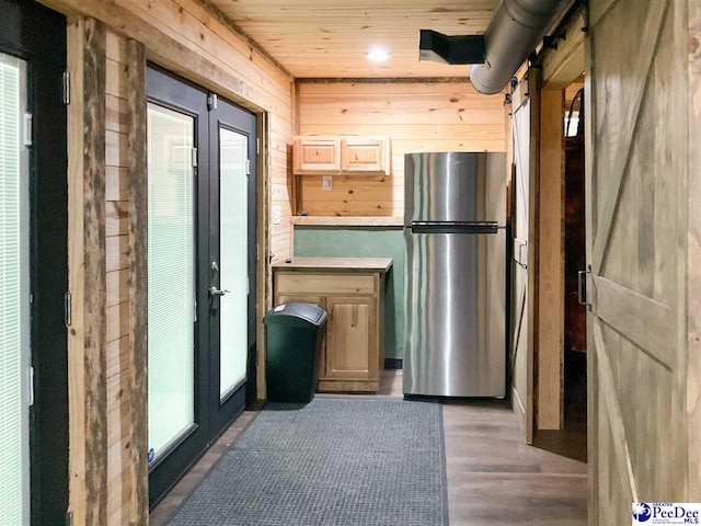 interior space featuring wood ceiling, light brown cabinets, freestanding refrigerator, wooden walls, and dark wood finished floors