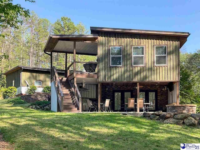 back of house featuring a lawn, stairway, board and batten siding, and stone siding