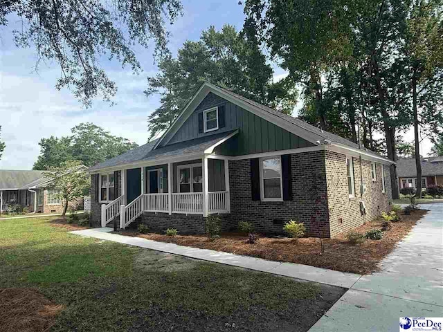 418 S Thomas Rd, Florence, SC 29501 - view of front of property with a porch, crawl space, brick siding, a front yard, and board and batten siding
