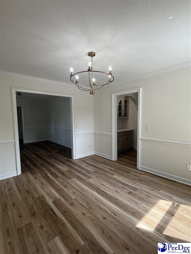 418 S Thomas Rd, Florence, SC 29501 - unfurnished dining area with a chandelier, arched walkways, ornamental molding, dark wood finished floors, and a textured ceiling