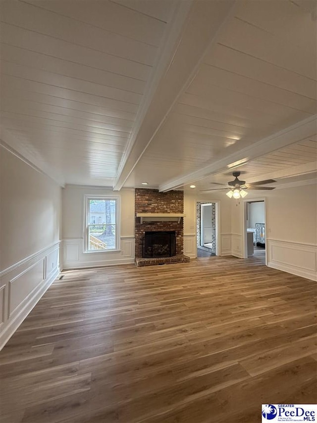 418 S Thomas Rd, Florence, SC 29501 - unfurnished living room featuring a decorative wall, wood finished floors, a brick fireplace, crown molding, and wood ceiling with exposed beams