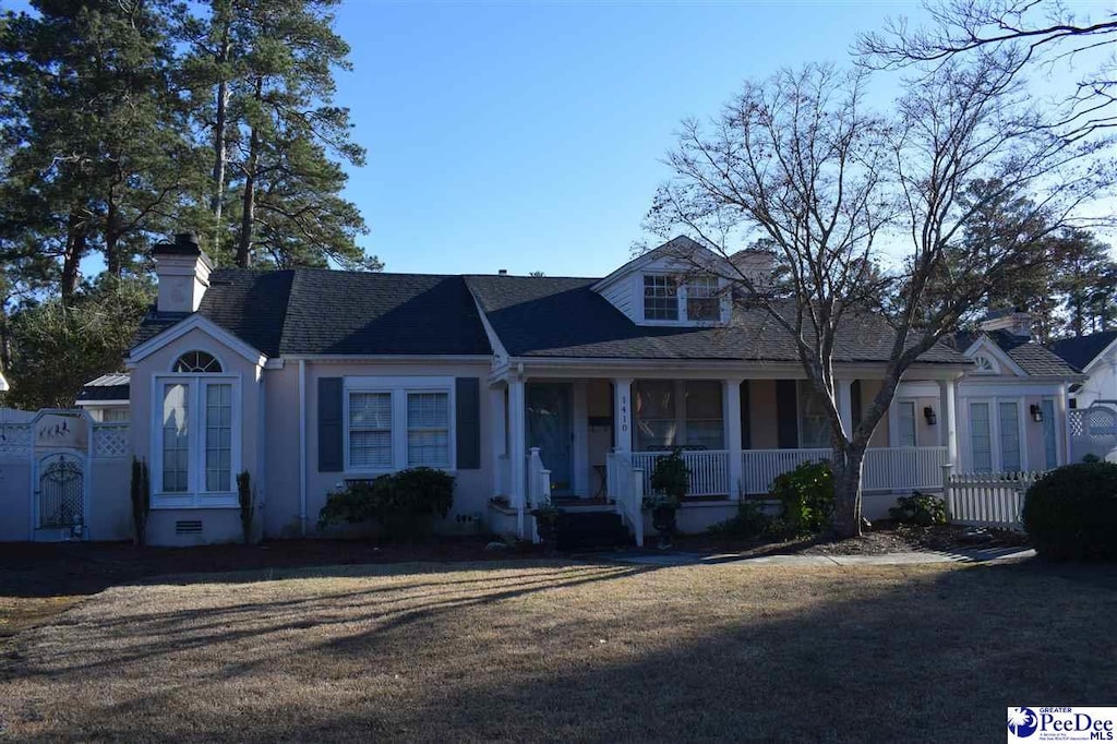 view of front of house with a porch, a chimney, and fence