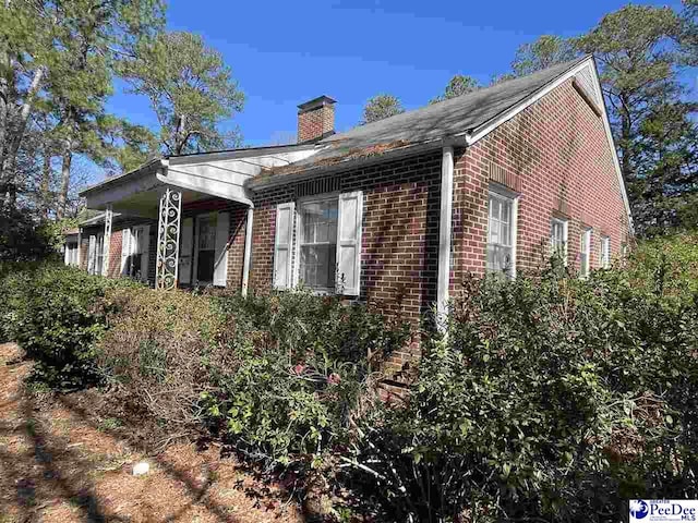 view of property exterior with brick siding and a chimney