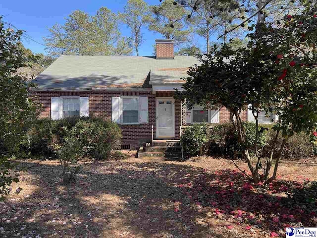 view of front of home featuring entry steps, a chimney, and brick siding