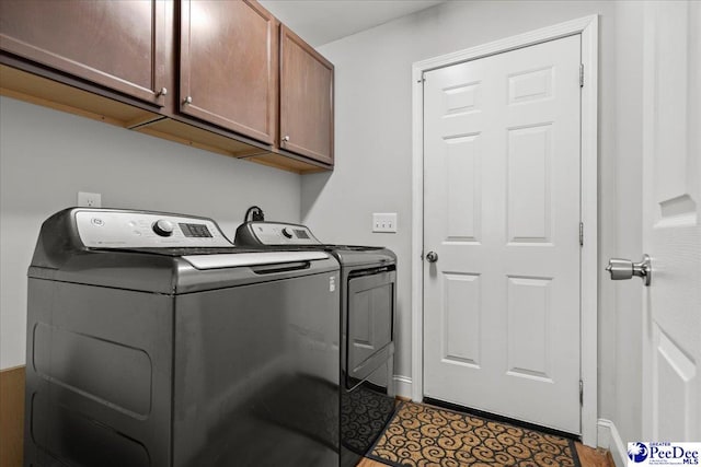 washroom featuring washing machine and dryer, baseboards, and cabinet space
