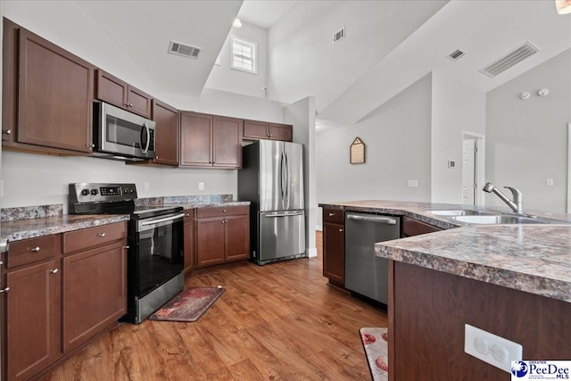 kitchen featuring visible vents, appliances with stainless steel finishes, high vaulted ceiling, and a sink