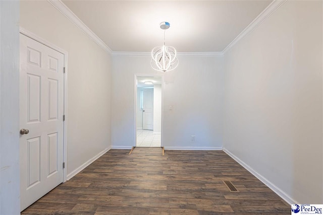 spare room featuring an inviting chandelier, wood finished floors, baseboards, and ornamental molding