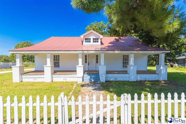 view of front of home featuring metal roof, covered porch, a fenced front yard, and a front yard