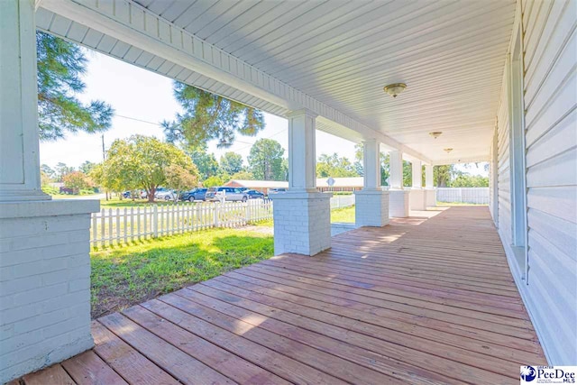 wooden terrace with covered porch, a lawn, and fence