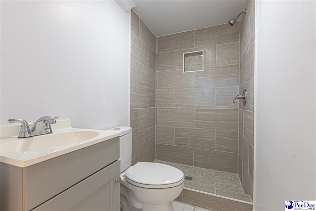 bathroom featuring tiled shower, toilet, and vanity