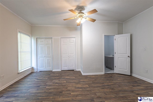 unfurnished bedroom featuring baseboards, dark wood-type flooring, ornamental molding, and a ceiling fan