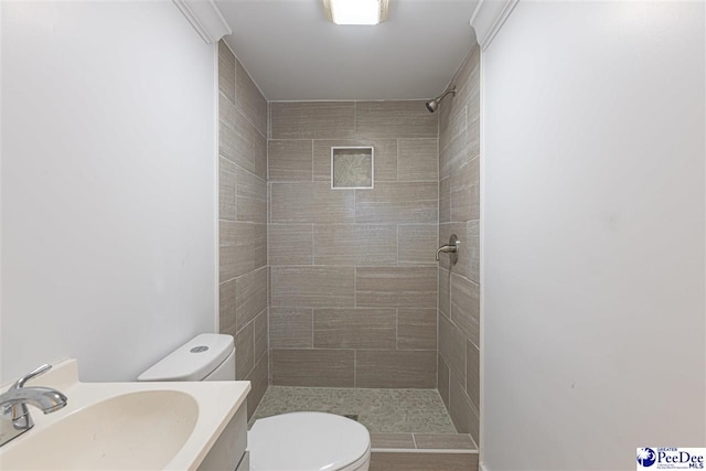 bathroom featuring toilet, vanity, and a tile shower