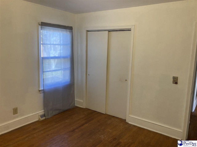 unfurnished bedroom with a closet and dark hardwood / wood-style floors