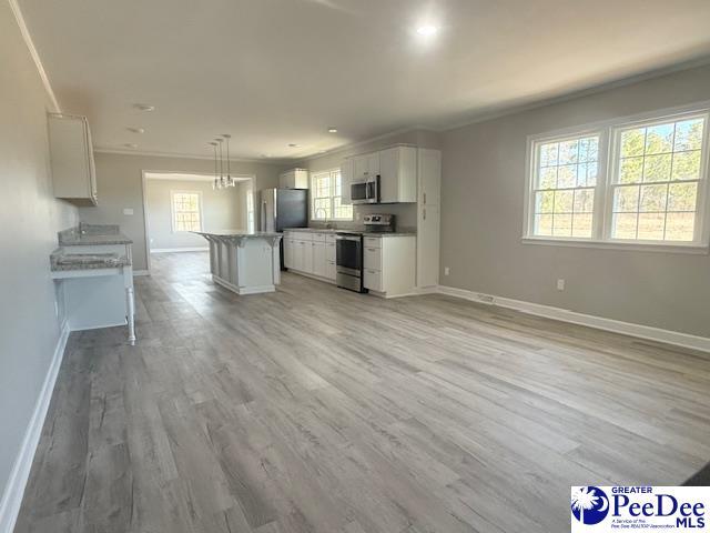 kitchen featuring white cabinets, light wood-style flooring, stainless steel appliances, and crown molding