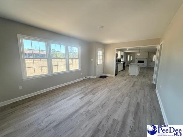 unfurnished living room featuring light wood-style floors and baseboards