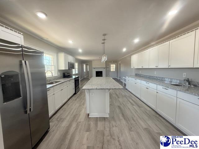 kitchen featuring appliances with stainless steel finishes, white cabinets, a sink, and a kitchen island